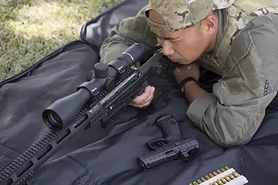 Man on stomach looking through a Burris riflescope mounted on a ar-15